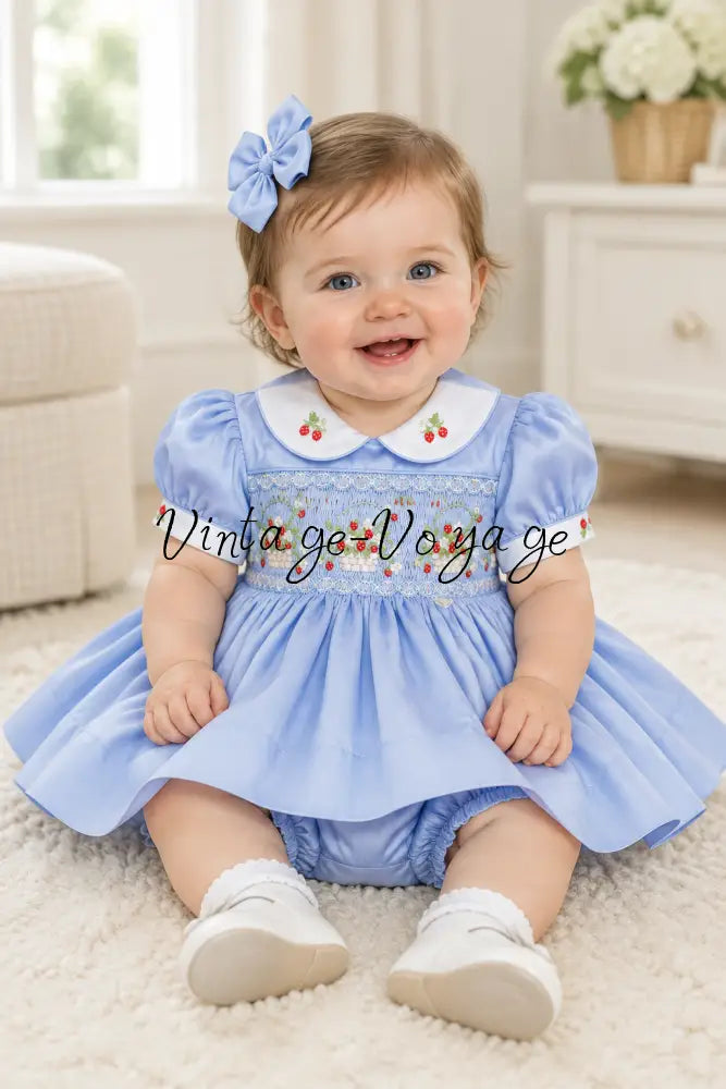 Baby model wearing the baby-blue strawberry smocked dress