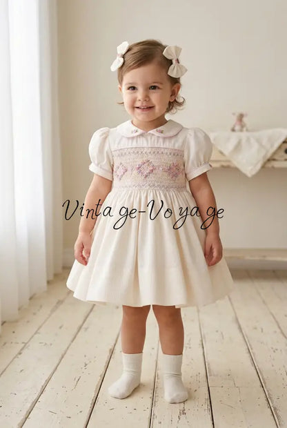 Toddler wearing the ivory dress and socks with two matching hair bows instead of a headband
