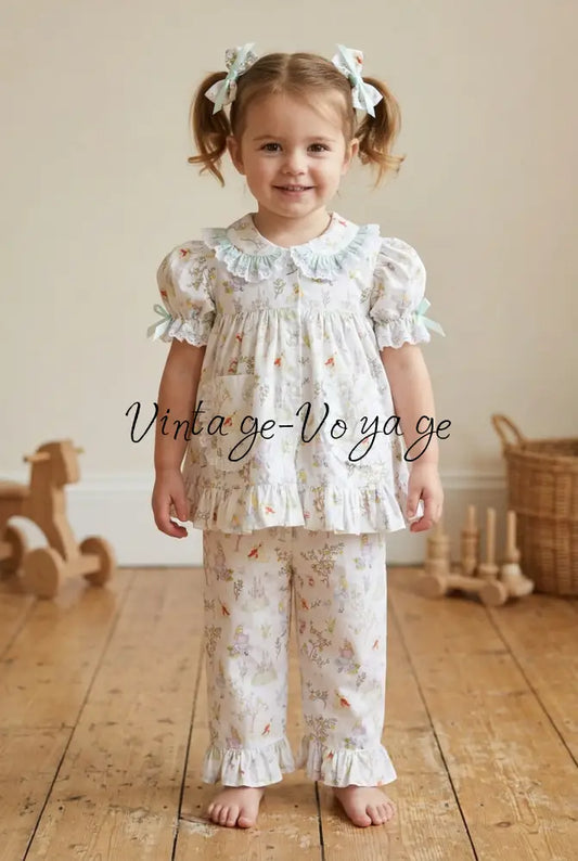 Toddler model wearing the Alice in Wonderland pyjama set with two matching hair bows